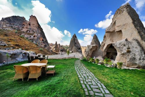 une table et des chaises dans un champ avec des rochers dans l'établissement Anatelein Boutique Cave Hotel, à Uçhisar