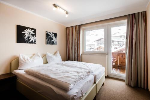 1 dormitorio con cama y ventana en Aparthotel Dorfplatzl Garni en Tux