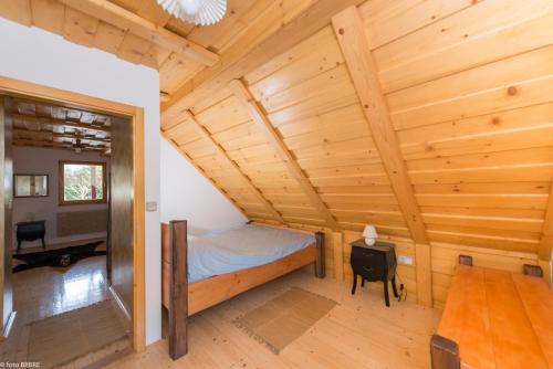 1 dormitorio en una cabaña de madera con 1 cama y 1 mesa en Koča na Planini, en Planina pod Sumnikom