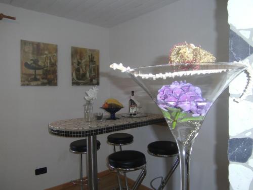 a bar with stools and a martini glass with purple flowers at Ferienwohnung Rosentraum in Oberotterbach
