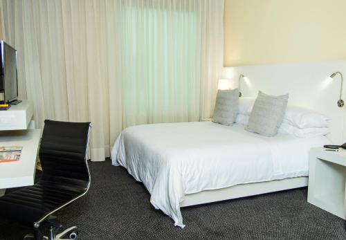 a hotel room with a bed and a desk and a television at Movich Buro 26 in Bogotá