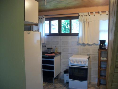 a kitchen with a stove and a refrigerator at Chalés Vale Verde in Visconde De Maua