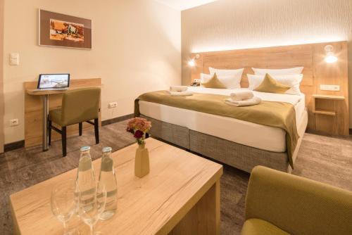 a hotel room with a bed and a table with two bottles on it at Am Schloßbrunnen Bad Muskau in Bad Muskau