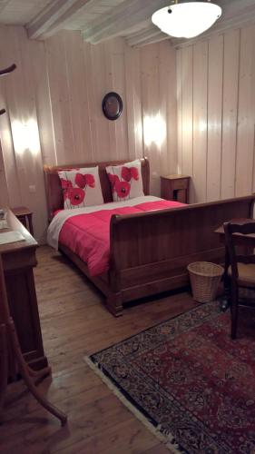 a bedroom with a bed with red sheets and pink pillows at Chambre d Hote 1873 in Frasne