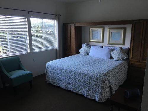 a bedroom with a bed and a chair and windows at Pine Acres Lodge in Pacific Grove