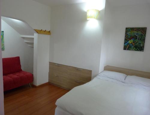a bedroom with a bed and a red chair at Casa Jade in Rionegro