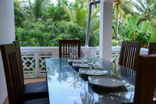a table with chairs and wine glasses on a patio at Ravi Villa Hikkaduwa in Hikkaduwa