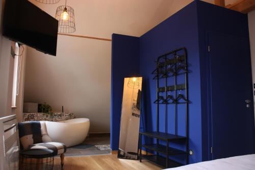 a room with a blue wall with a chair and a mirror at Théière & Couverts - Les Chambres in Cernay