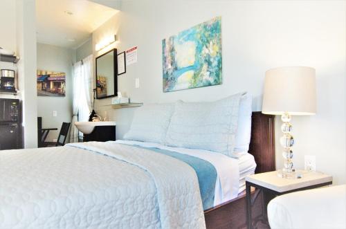 a bedroom with a white bed and a table with a lamp at Hotel Royal in Long Beach