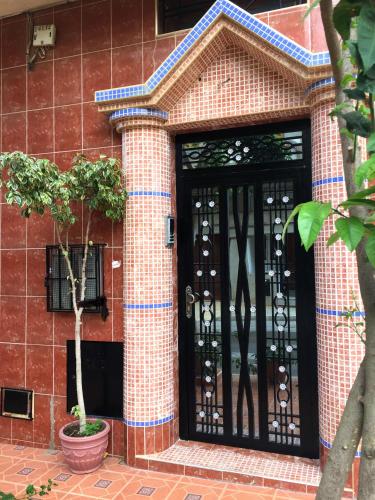 a brick building with a black door and two trees at Dar Rachid in Asilah