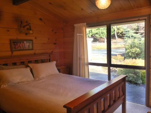 ein Schlafzimmer mit einem Bett und einem großen Fenster in der Unterkunft Pukaki Lakeside Getaway NZ in Lake Pukaki