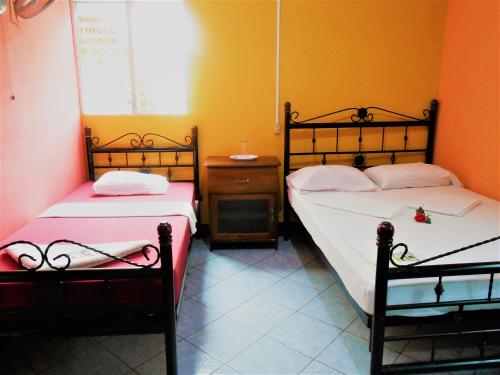 a bedroom with two beds and a table and a window at Hostal Siero in Moyogalpa