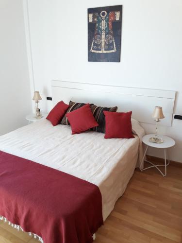 a bedroom with a large bed with red pillows at Big and Bright Apartment in Corralejo