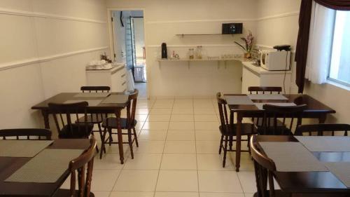 a restaurant with tables and chairs and a kitchen at Pousada Villa Branca - Petar (Apiaí-SP) in Apiaí