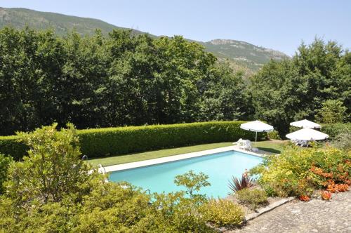 a swimming pool in a garden with umbrellas at Quinta de Albergaria in Facha