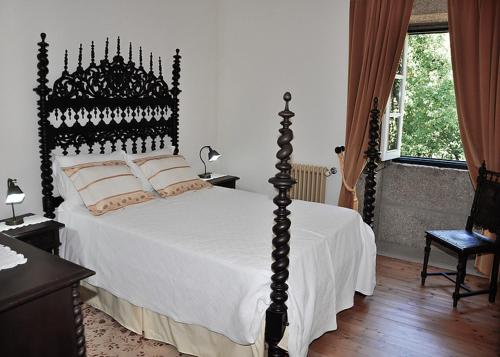 a bedroom with a black and white bed with white sheets at Quinta de Albergaria in Facha