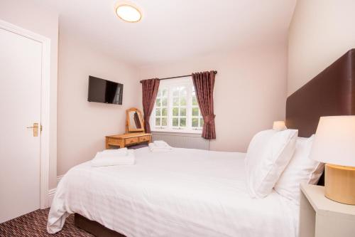 a bedroom with a white bed and a window at The Burley Inn in Burley