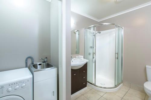 a bathroom with a shower sink and a washing machine at Quest On Ward Serviced Apartments in Hamilton