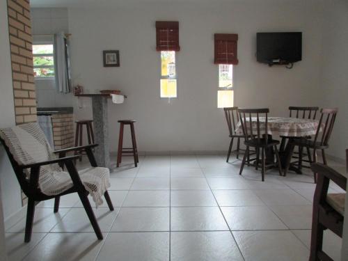 Canto dos Pássaros Apartamentos في فلوريانوبوليس: غرفة معيشة مع طاولة وكراسي وتلفزيون