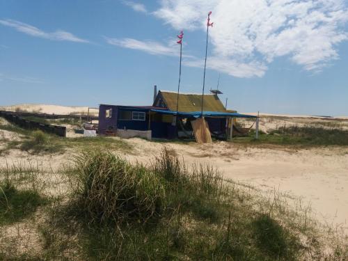 a house on the beach with a flag on it at cabopolonioalojamiento in Cabo Polonio