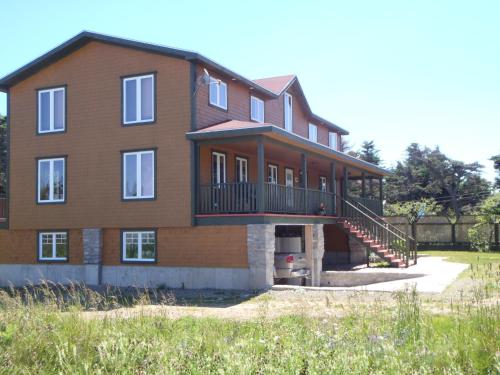 a large brick house with a porch and a balcony at Gîte La Maison Chez J.P. Bed and Breakfast in Havre aux Maisons