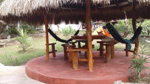 a table and chairs under a straw umbrella at Chelle's Guesthouse and Backpackers in Siquijor