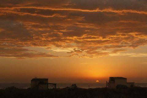 a sunset with the sun setting in the horizon at cabopolonioalojamiento in Cabo Polonio