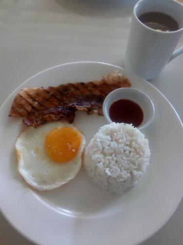 a plate of food with eggs bacon rice and a cup of coffee at Orange Mangrove Pension House by SMS Hospitality in Puerto Princesa City