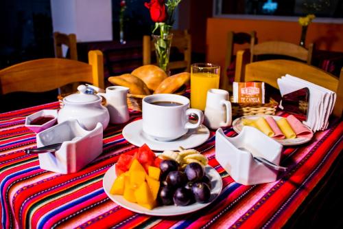 una mesa con desayuno de fruta y una taza de café en Hostal Los Andes, en Cusco