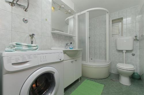 een wasmachine in een badkamer met een toilet en een wastafel bij Apartment Josipa in Primošten