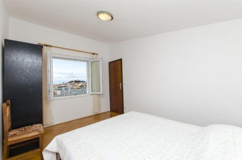 a white bedroom with a bed and a window at Apartment Josipa in Primošten