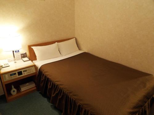 a hotel room with a bed and a lamp on a table at Southern Cross Inn Matsumoto in Matsumoto