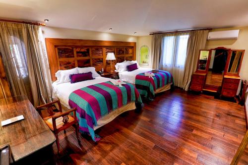 a bedroom with two beds and a wooden floor at Pensativo House Hotel in Antigua Guatemala