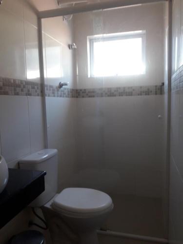 a white bathroom with a toilet and a window at Hotel Morada do Mar in Guarujá