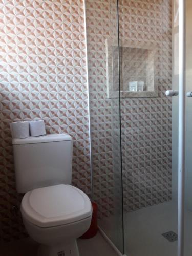 a bathroom with a toilet and a glass shower at Hotel Morada do Mar in Guarujá
