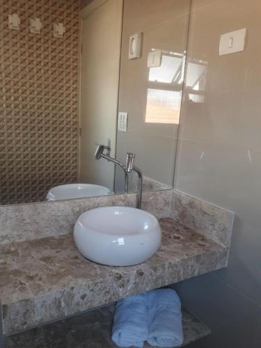 a bathroom counter with a sink and a mirror at Hotel Morada do Mar in Guarujá