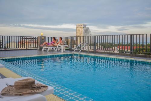 two women sitting on chairs next to a swimming pool at Baan Nilrath Hotel - SHA Extra Plus in Hua Hin