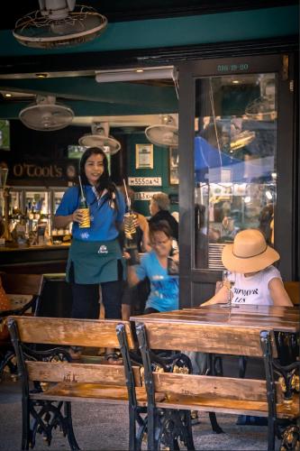 a woman standing next to a table in a restaurant at Angus O'Tool's Guesthouse in Karon Beach