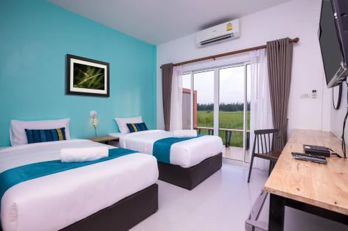 a hotel room with two beds and a balcony at Xaiyong Resort - ไทรโยงรีสอร์ท in Buriram