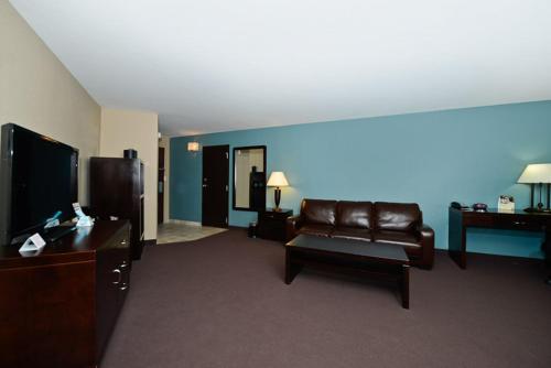 a living room with a leather couch and a tv at Causeway Bay Hotel in Lansing