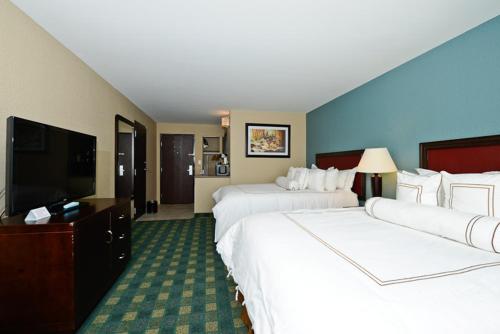 a hotel room with two beds and a flat screen tv at Causeway Bay Hotel in Lansing