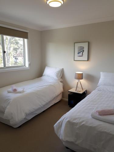 a bedroom with two beds with a window and a lamp at Blue on Cooper in Katoomba