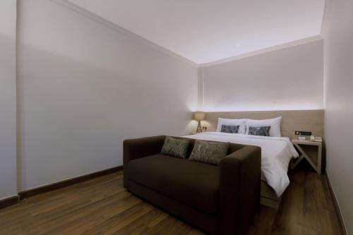 a bedroom with a bed and a couch at Maxim's Inn in Bangkok