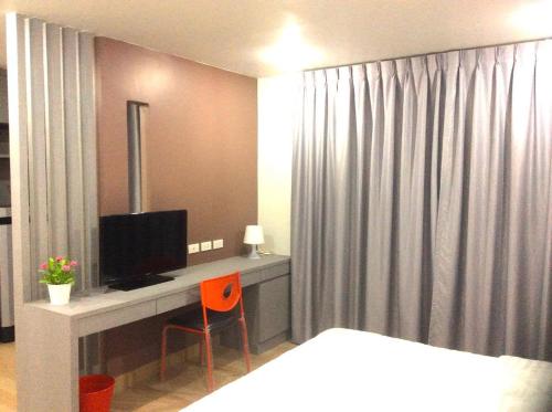 a bedroom with a bed and a desk with a television at Live at Home Sukhumvit 105 in Bangkok
