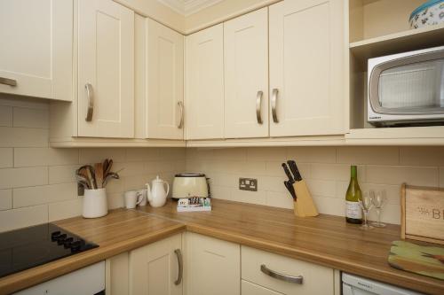 a kitchen with white cabinets and a wooden counter top at The Osborne Apartments in Torquay