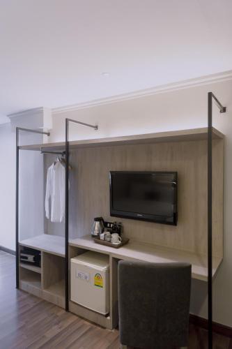 a room with a tv and a desk with a chair at Maxim's Inn in Bangkok