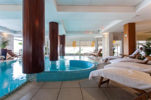 リド・ディ・イエゾロにあるHotel Villa Sorrisoのベッドとスイミングプール付きのホテル内のプールを提供しています。