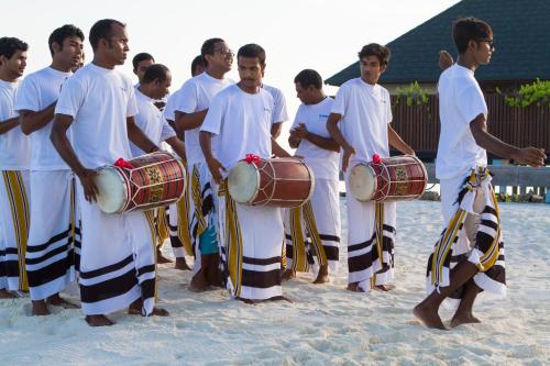 a group of men standing on the beach holding drums at Summer Island Maldives in North Male Atoll