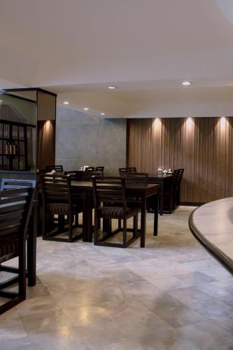 a dining room with wooden tables and chairs at Maxim's Inn in Bangkok