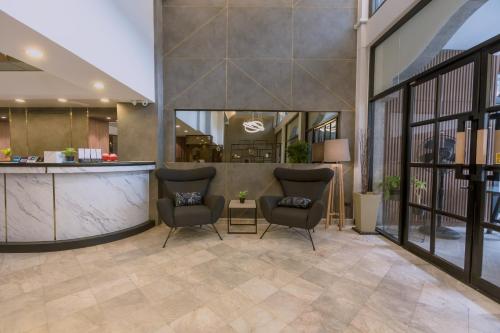 a lobby with two chairs and a bar at Maxim's Inn in Bangkok